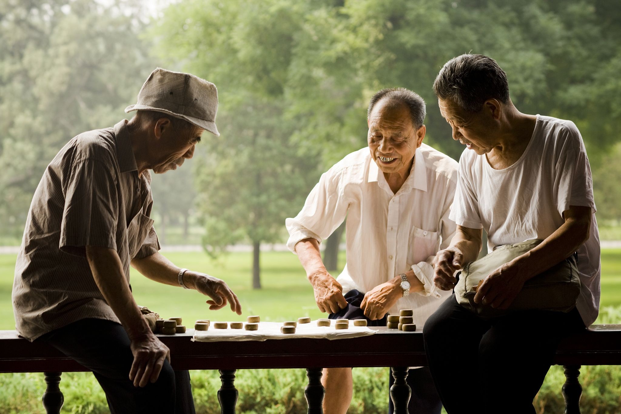 三个男人在户外微笑着玩棋盘游戏.jpg